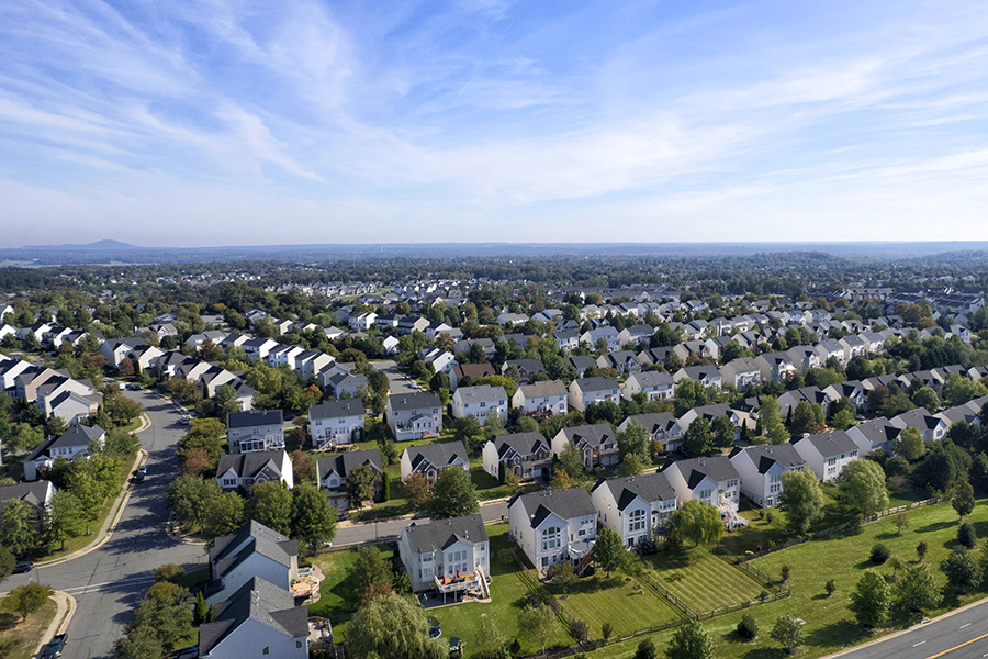 Aerial view of a Loudoun County neighborhood of single-family homes with tree-lined streets and open land beyond