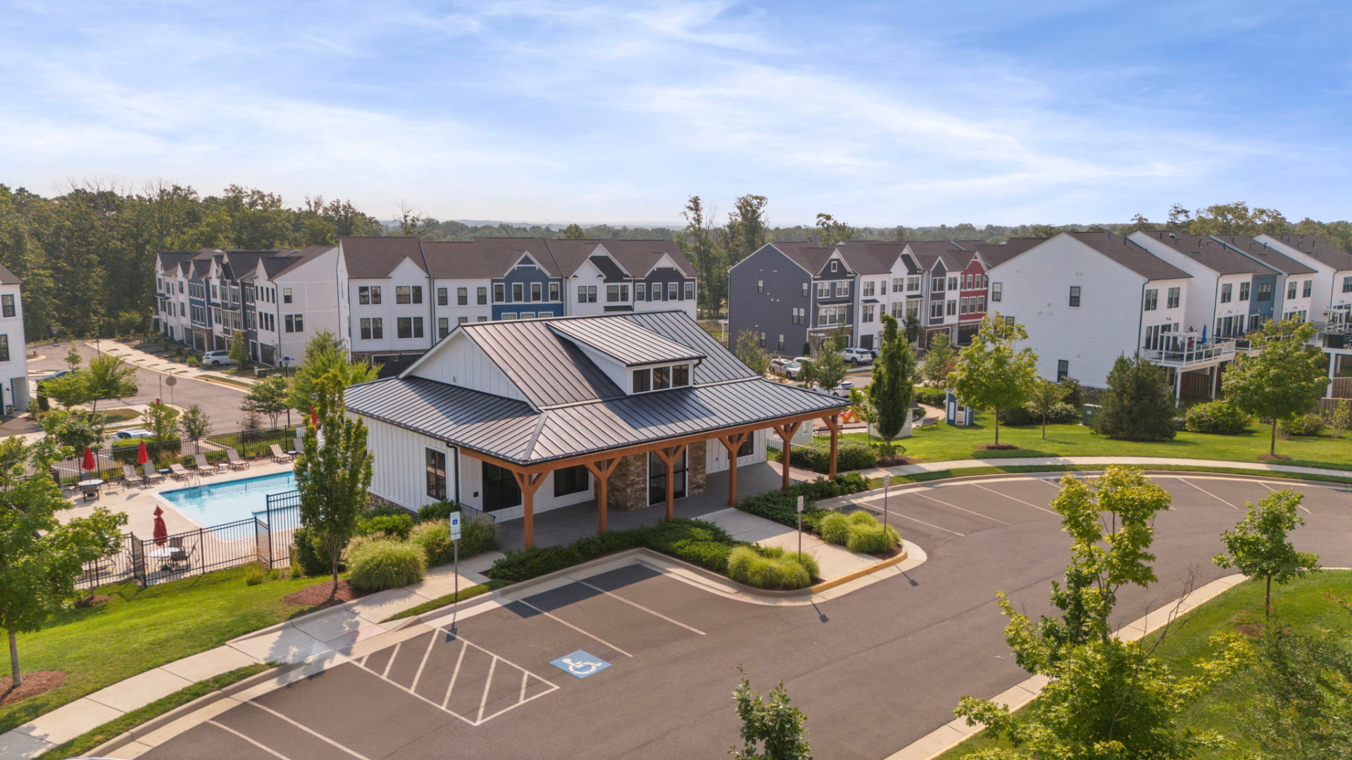 Aerial view of a newer townhome community with a clubhouse, covered porch, and outdoor pool